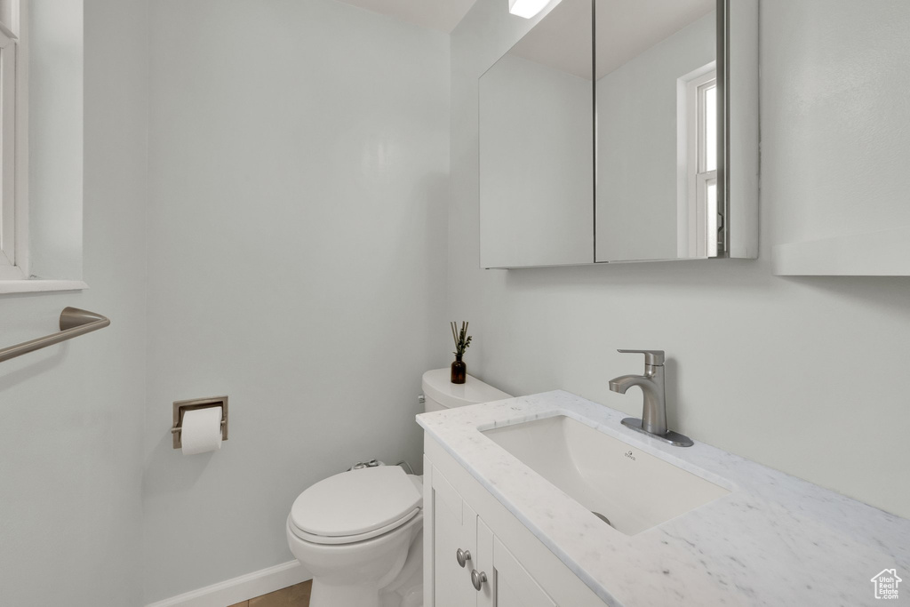 Half bathroom with vanity, toilet, and baseboards