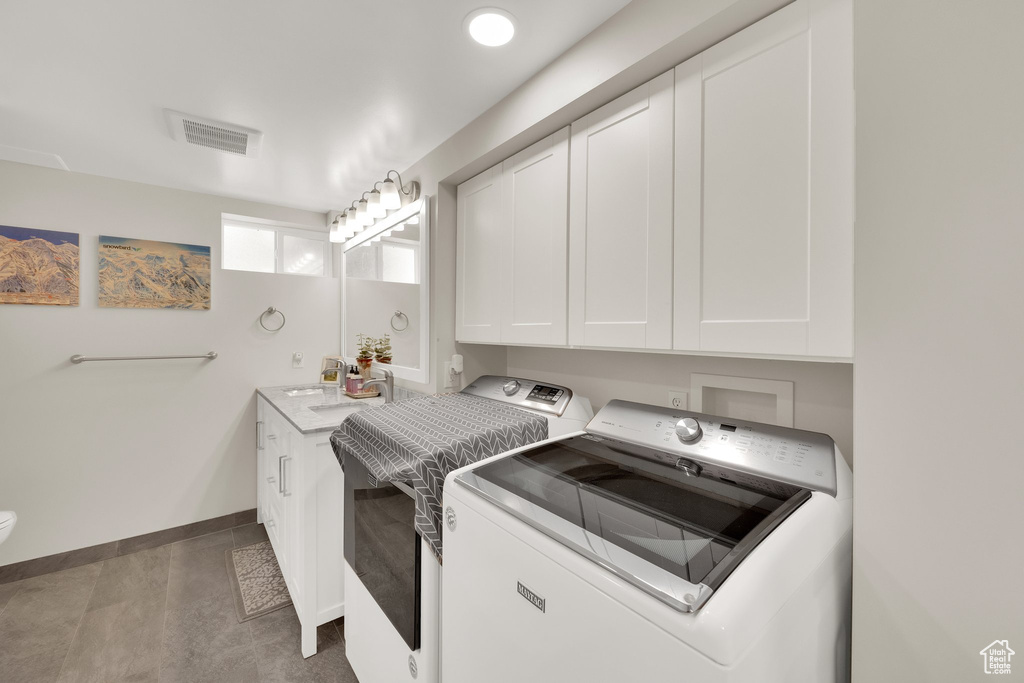 Laundry area with washer and dryer, baseboards, and a sink