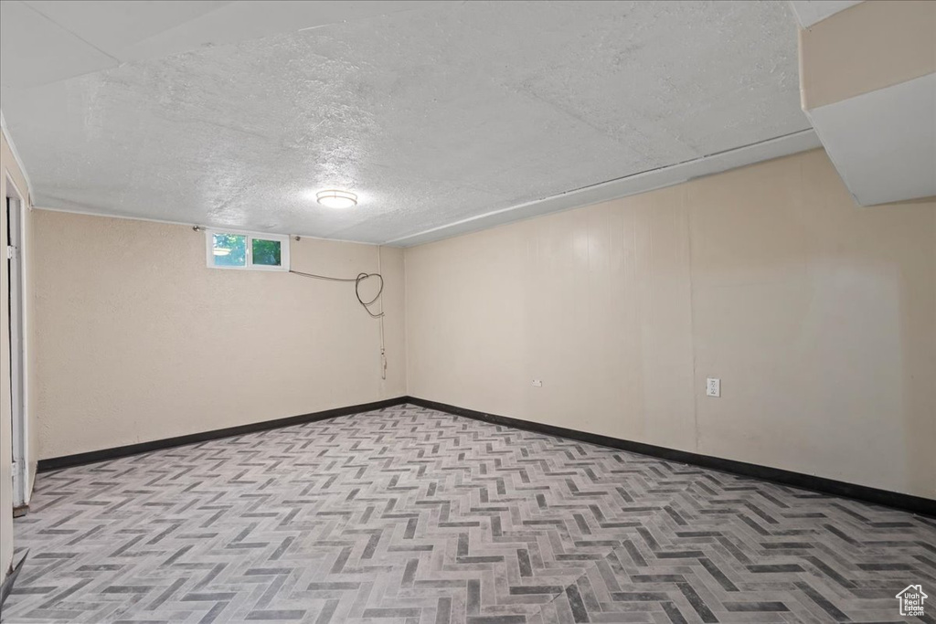 Basement featuring a textured ceiling and baseboards