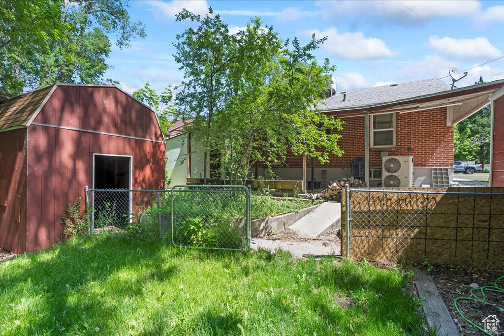 Rear view of house featuring an outdoor structure, a gambrel roof, brick siding, and ac unit