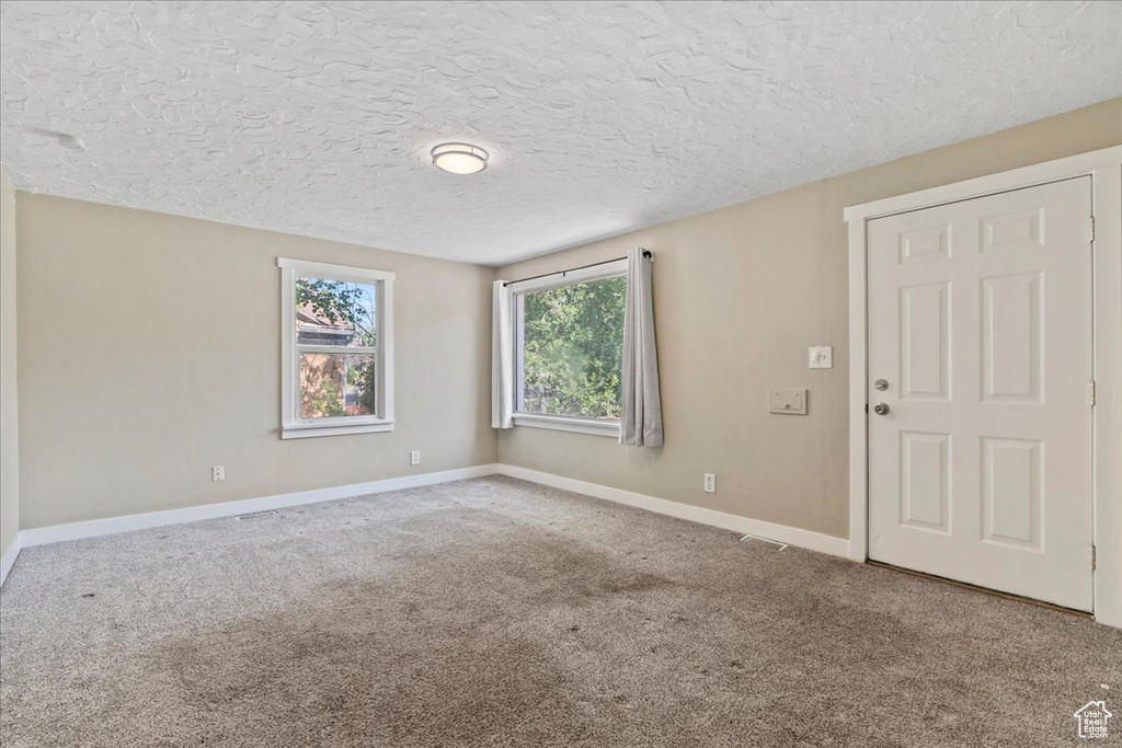 Carpeted spare room with baseboards and a textured ceiling