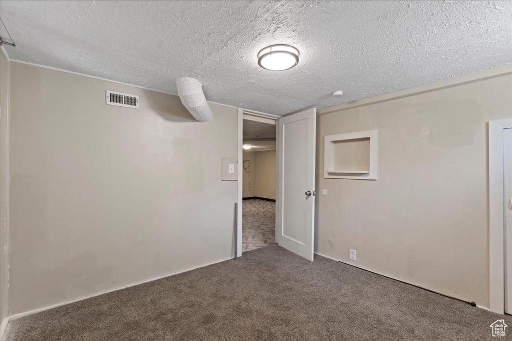 Carpeted empty room featuring a textured ceiling