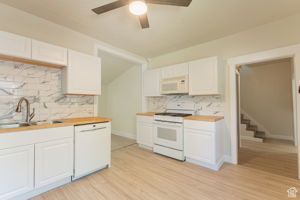 Kitchen featuring white appliances, a sink, wooden counters, and tasteful backsplash
