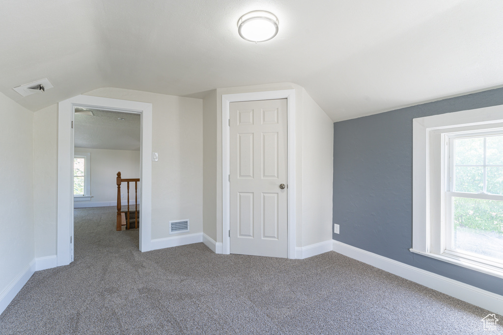 Bonus room featuring lofted ceiling, carpet floors, and baseboards