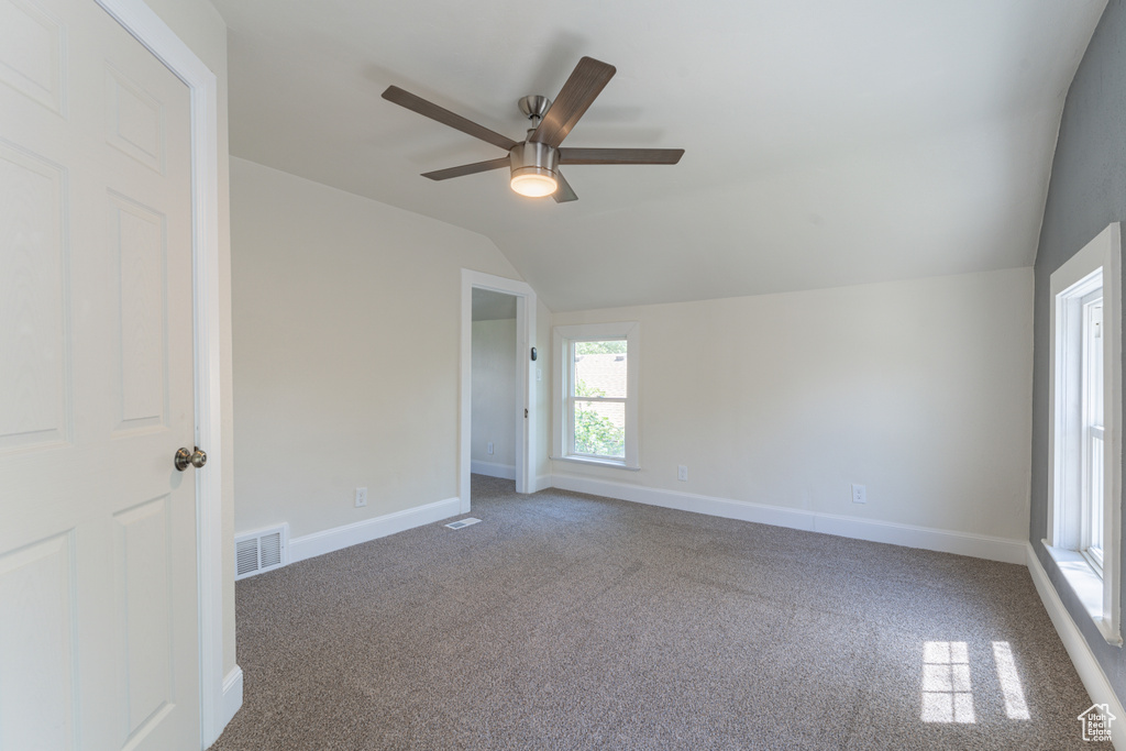 Empty room featuring lofted ceiling, ceiling fan, carpet flooring, and baseboards