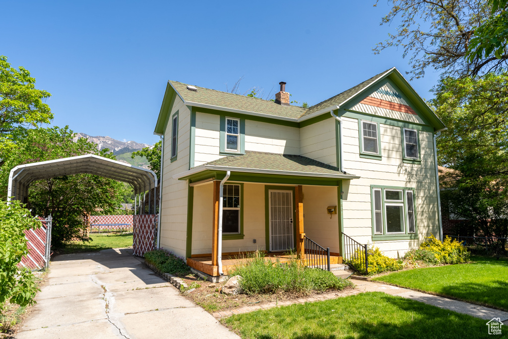 Victorian home featuring a carport, a porch, a shingled roof, a chimney, and a mountain view