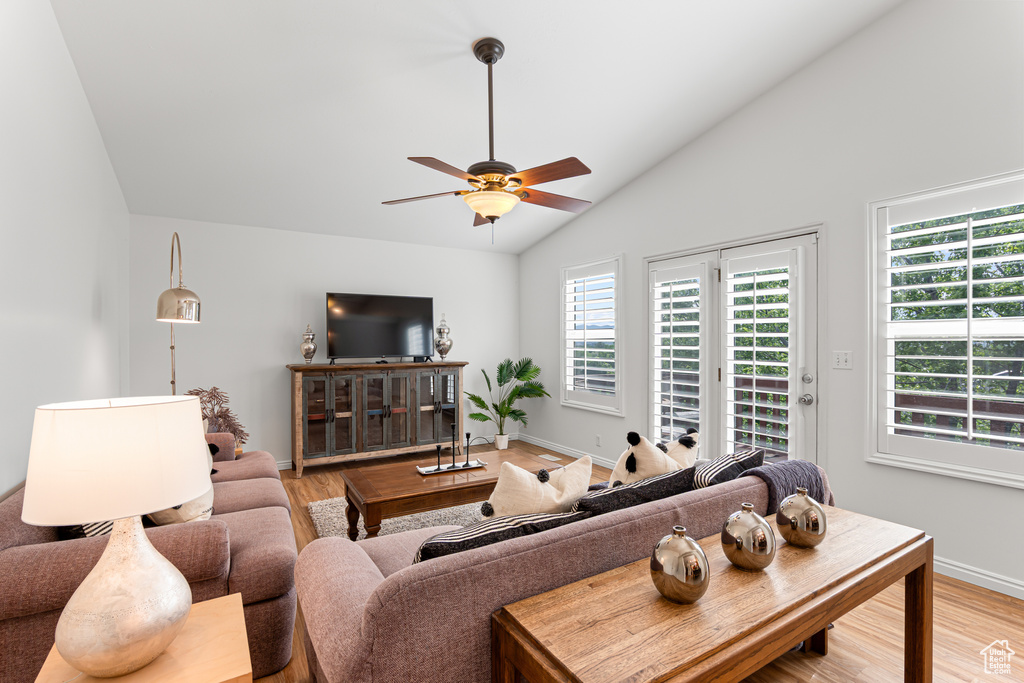 Living room with vaulted ceiling, light wood finished floors, ceiling fan, and baseboards