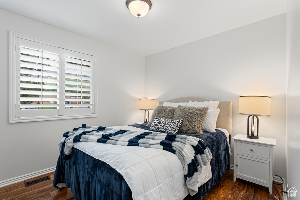 Bedroom with dark wood finished floors and baseboards