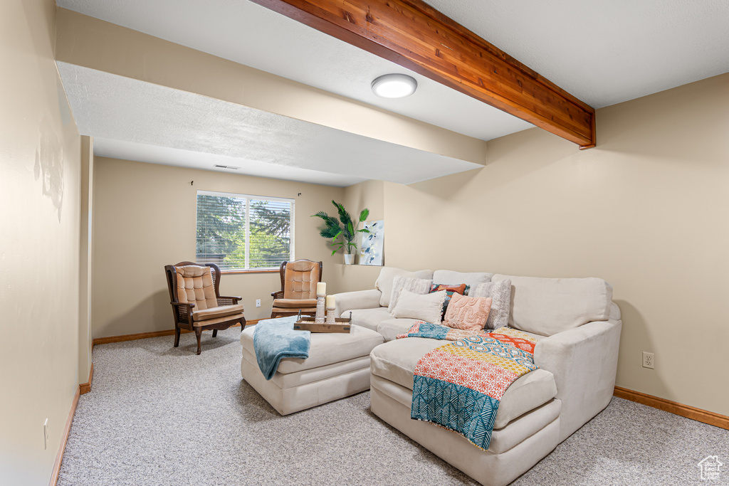 Carpeted living area featuring beamed ceiling and baseboards