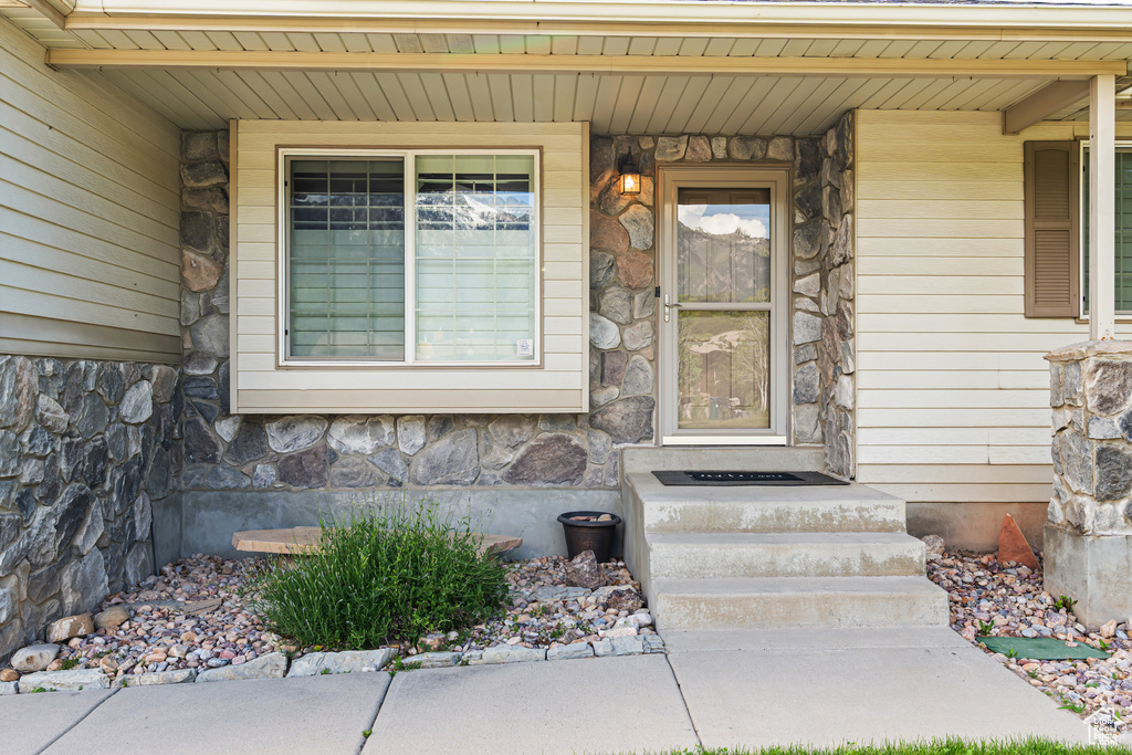 Doorway to property featuring stone siding and covered porch