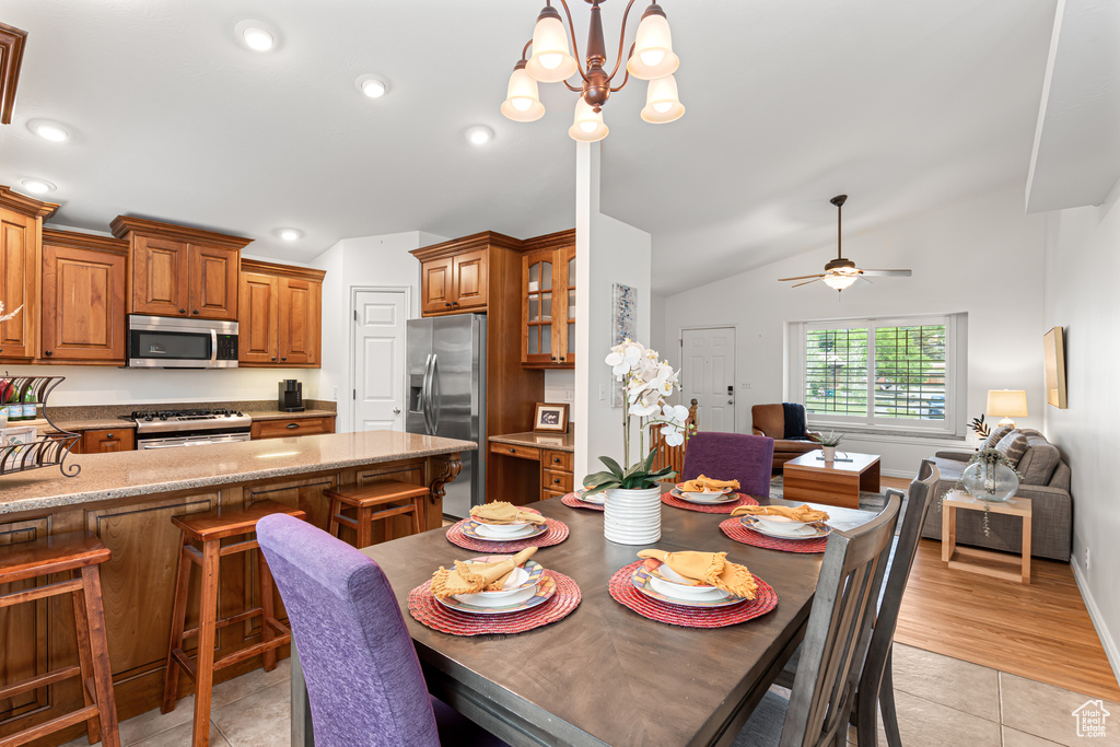 Dining space featuring lofted ceiling, a chandelier, light tile patterned flooring, recessed lighting, and ceiling fan
