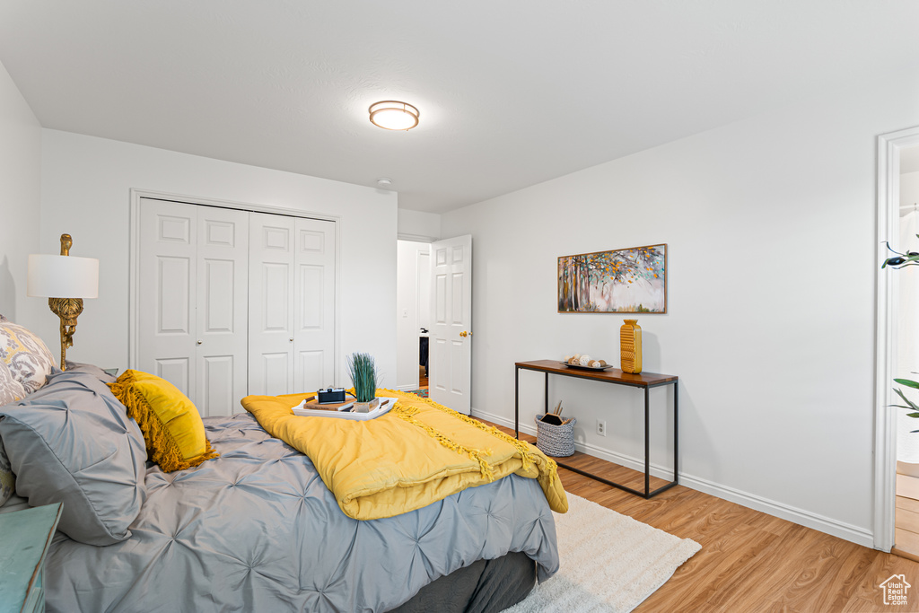 Bedroom with light wood-style floors, a closet, baseboards, and ensuite bathroom