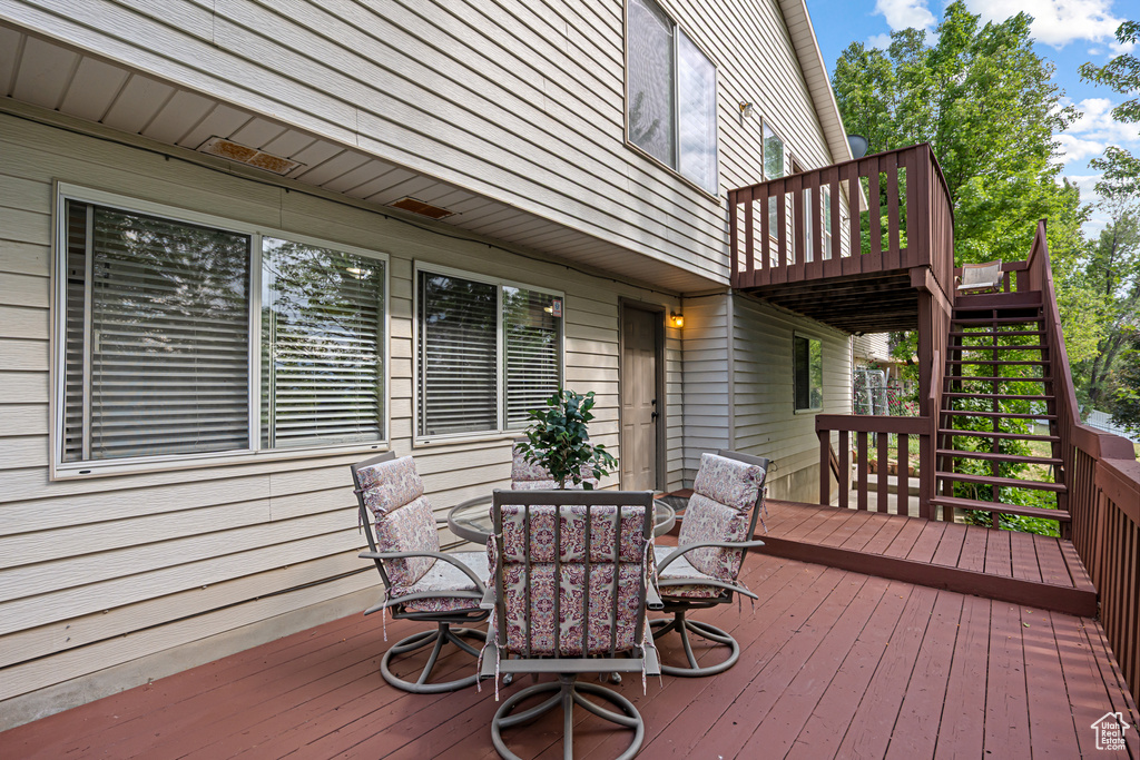 Wooden deck featuring outdoor dining space and stairs