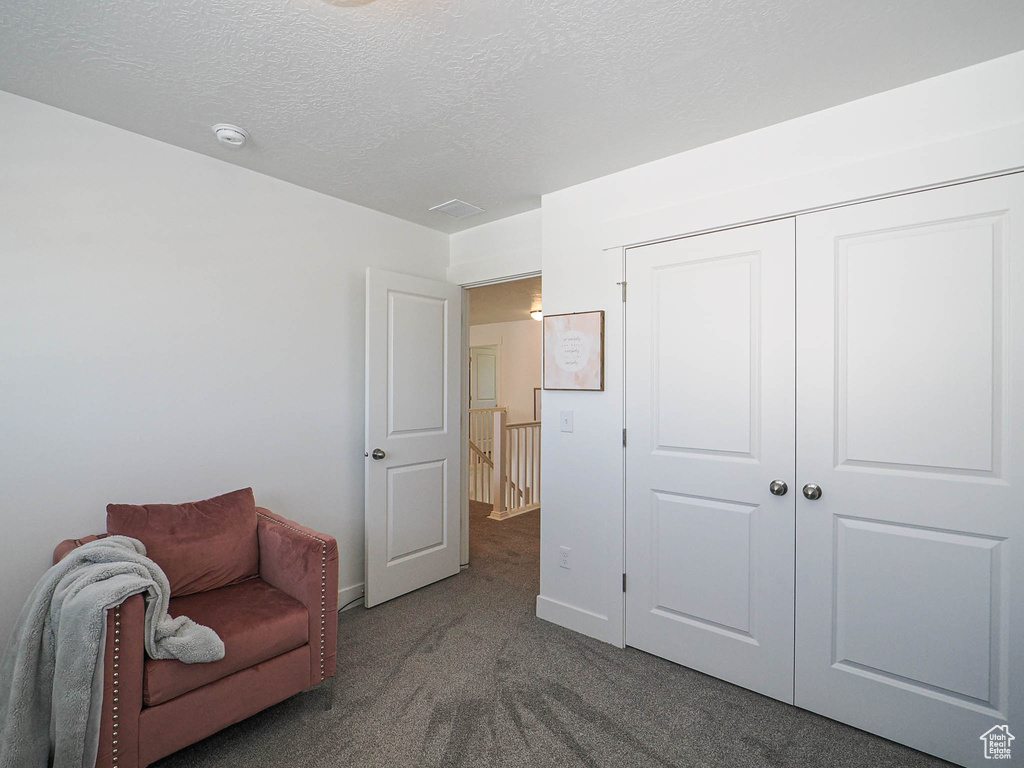 Living area with carpet flooring, a textured ceiling, and baseboards