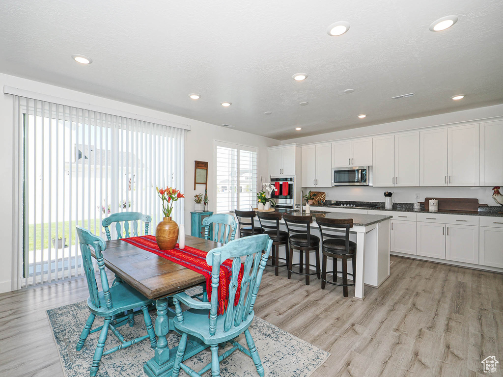 Dining space with light wood-style floors and recessed lighting