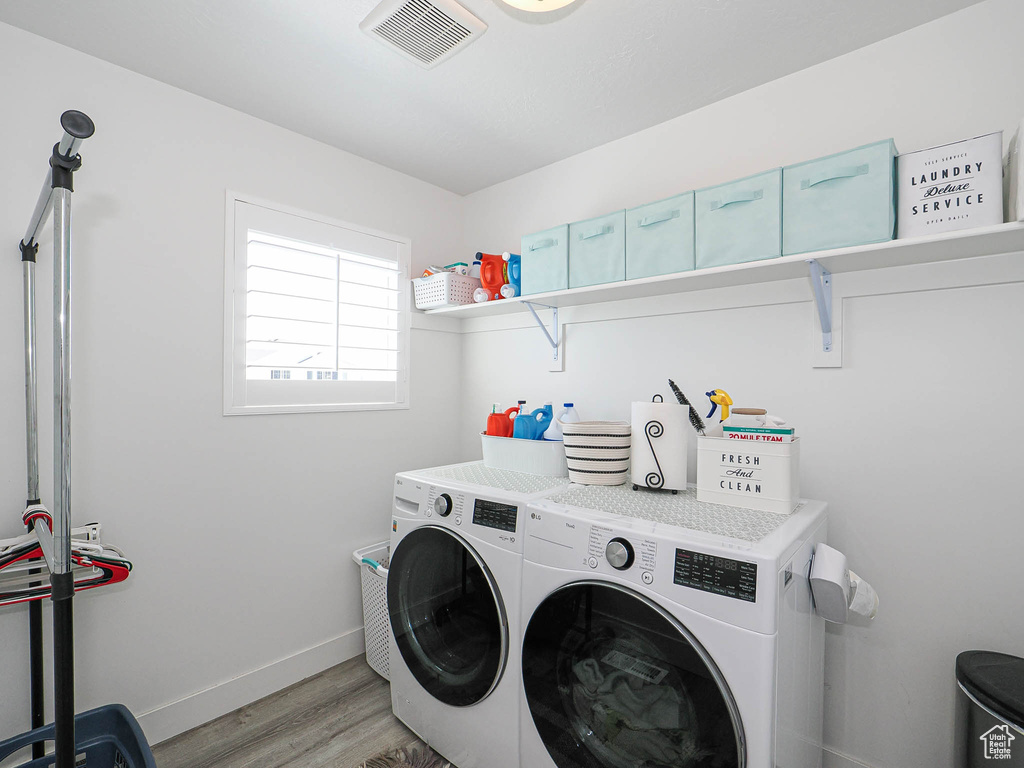 Washroom with washer and dryer, light wood-style flooring, and baseboards