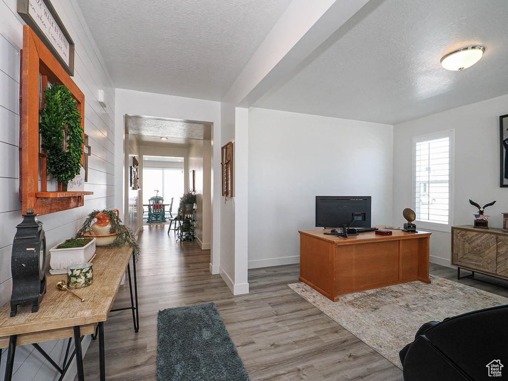 Home office featuring a textured ceiling, baseboards, and light wood-type flooring