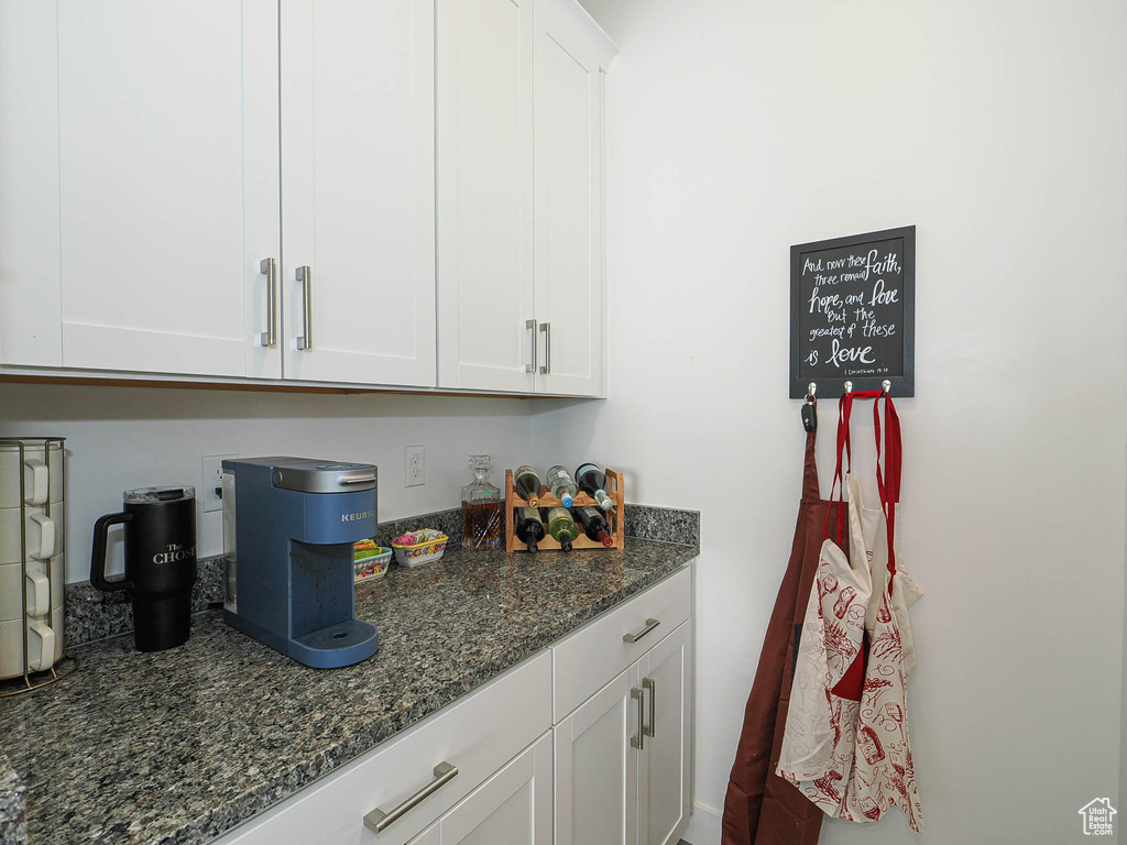 Kitchen with white cabinetry and dark stone countertops
