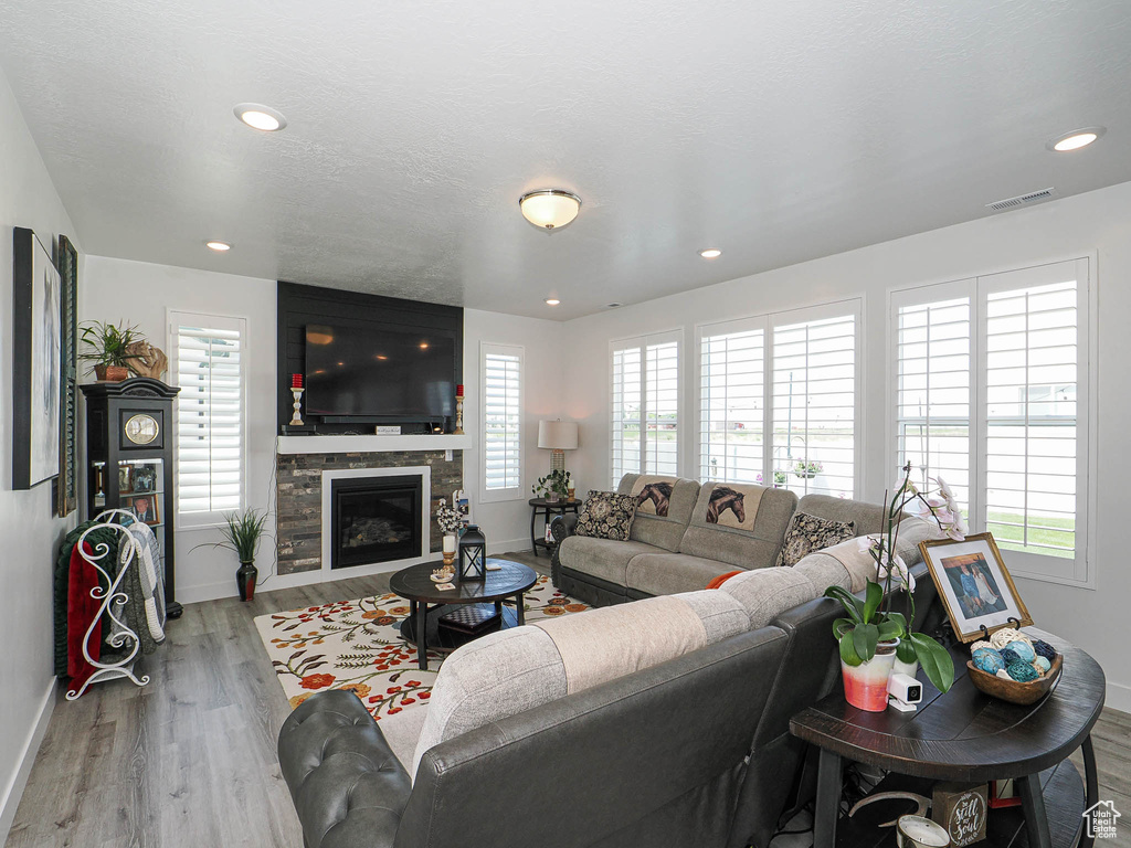 Living room featuring baseboards, wood finished floors, a glass covered fireplace, and recessed lighting