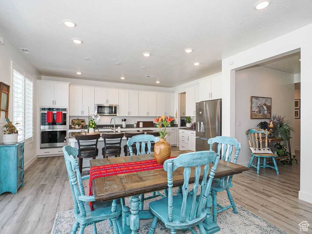 Dining room with light wood finished floors, recessed lighting, and baseboards