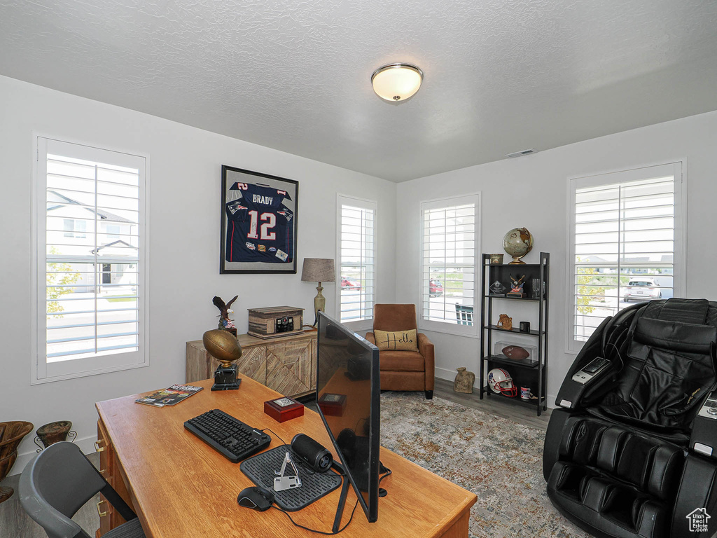 Office space with wood finished floors, baseboards, and a textured ceiling