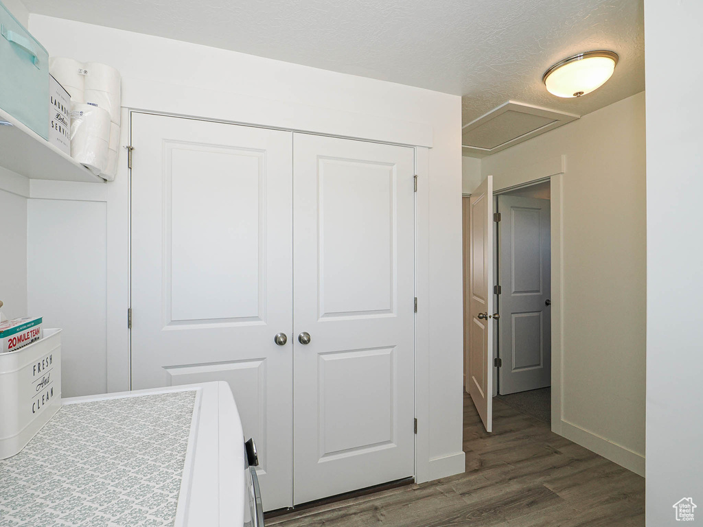 Bedroom featuring dark wood-style floors, a closet, baseboards, washer and dryer, and a textured ceiling
