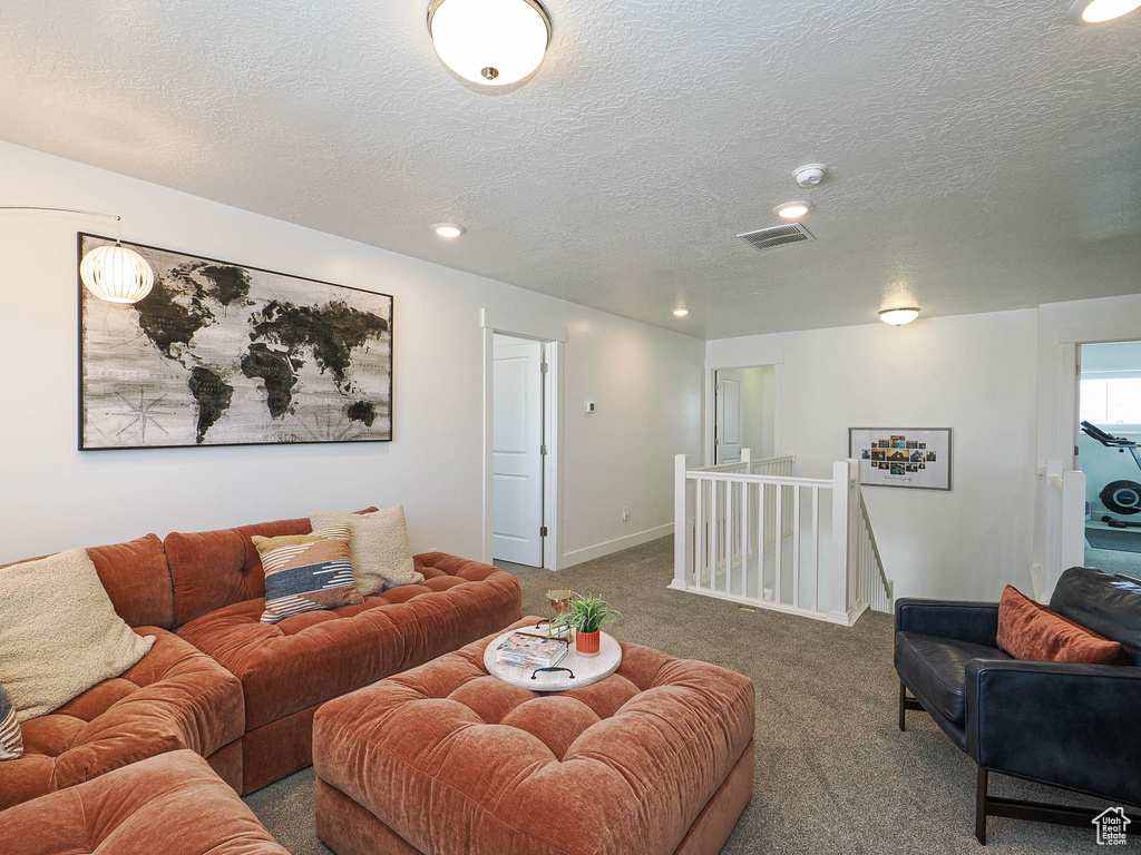 Carpeted living area featuring a textured ceiling, recessed lighting, and baseboards