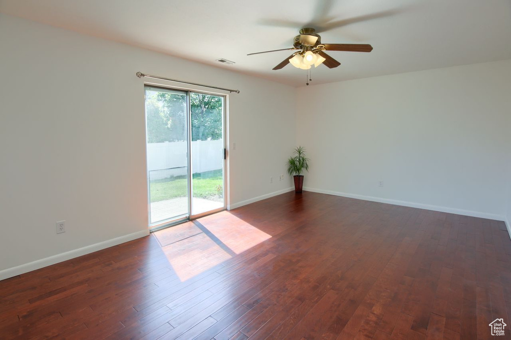 Unfurnished room featuring ceiling fan, dark wood-type flooring, and baseboards