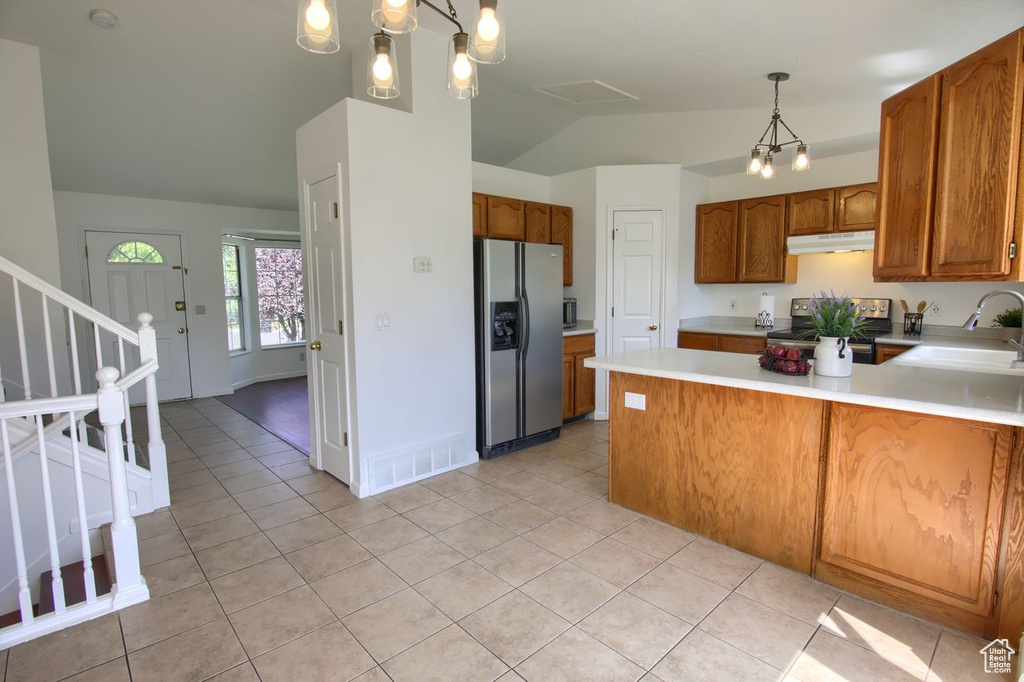 Kitchen featuring stainless steel appliances, under cabinet range hood, a sink, lofted ceiling, and light countertops