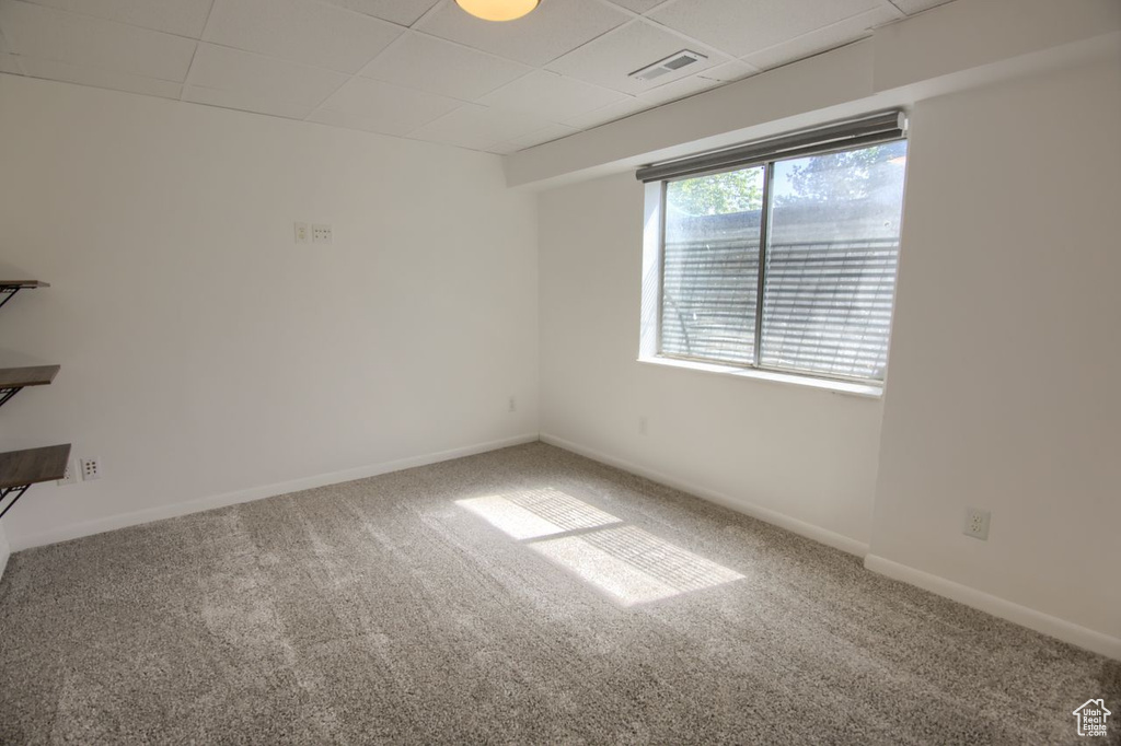 Unfurnished room featuring carpet, a paneled ceiling, and baseboards