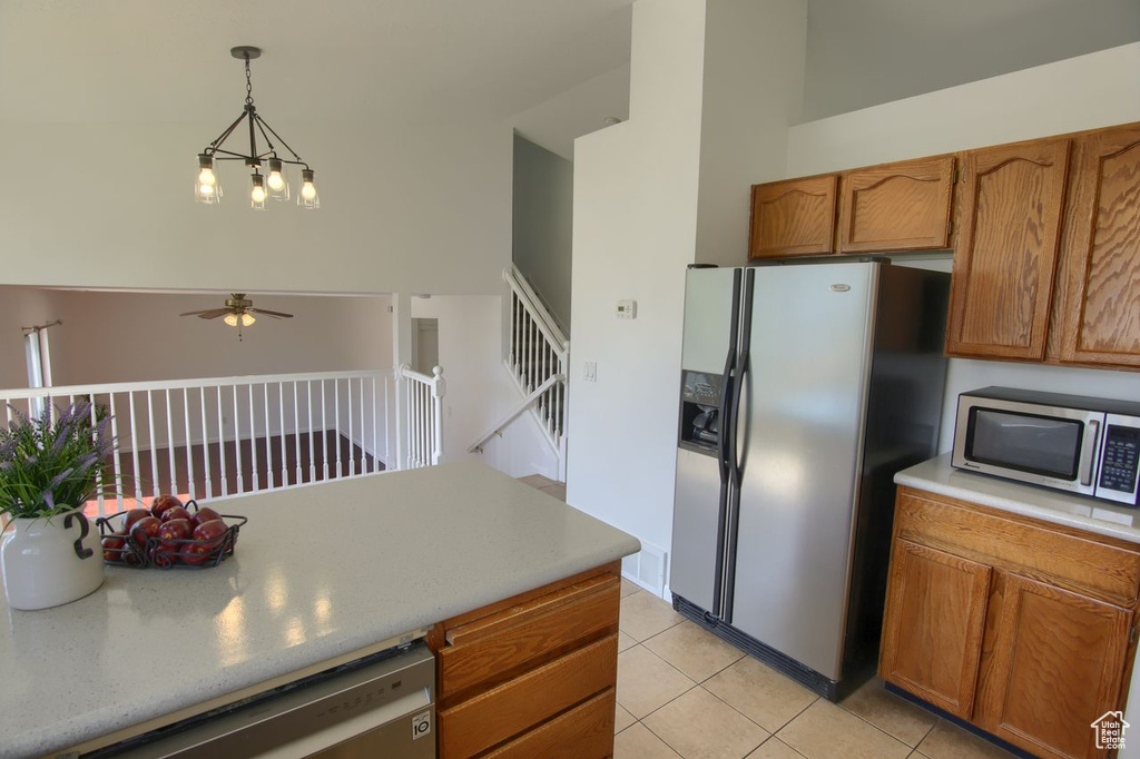 Kitchen with appliances with stainless steel finishes, a ceiling fan, light tile patterned floors, and brown cabinetry