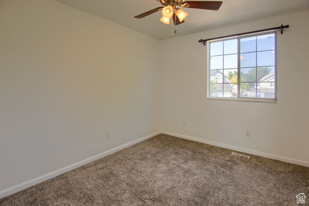 Spare room featuring carpet flooring, baseboards, and a ceiling fan