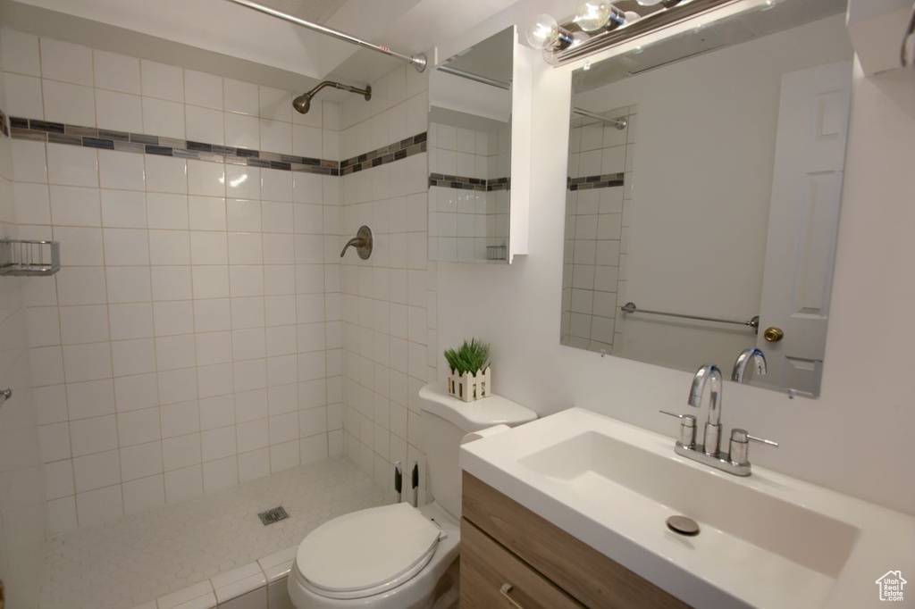 Bathroom with toilet, tiled shower, and vanity