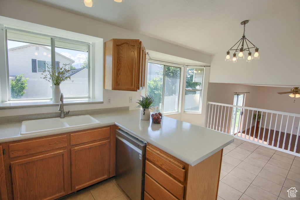 Kitchen with stainless steel dishwasher, a sink, a peninsula, light tile patterned floors, and light countertops