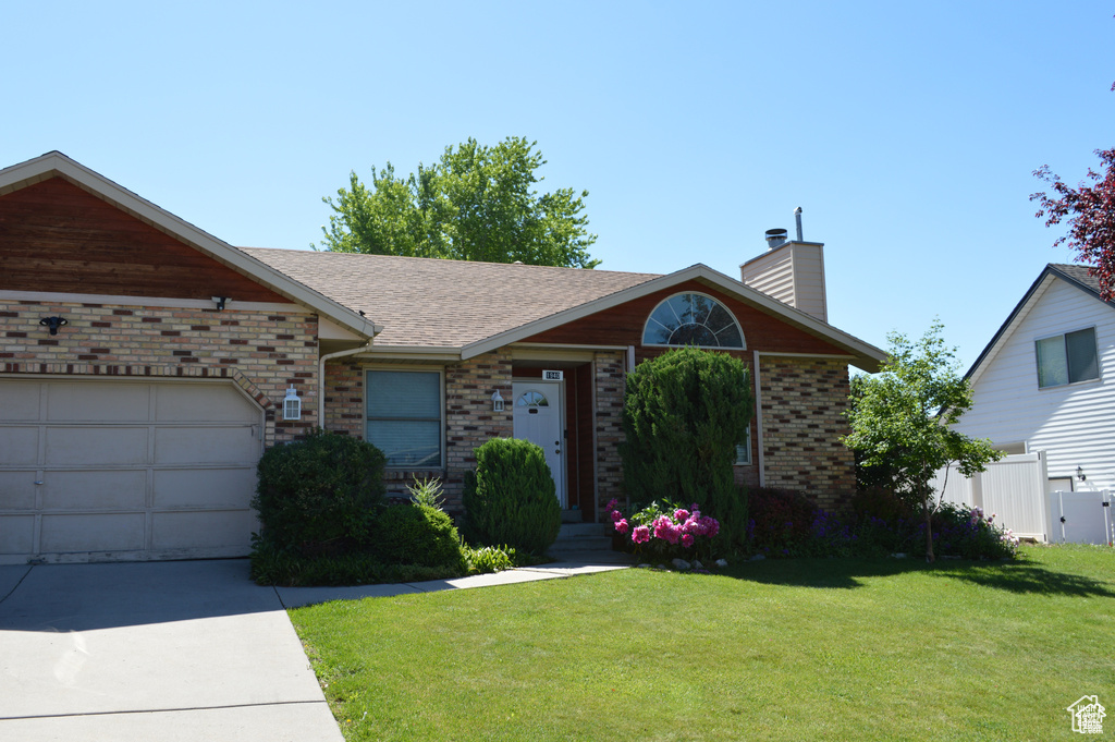 Ranch-style home with brick siding, a chimney, driveway, a garage, and a shingled roof