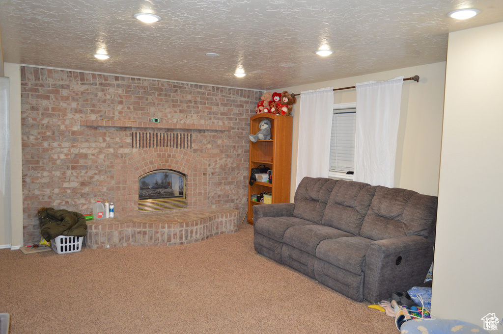 Living room featuring carpet floors, a fireplace, a textured ceiling, and recessed lighting