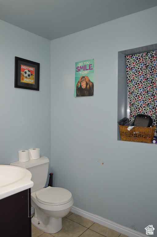 Bathroom with tile patterned floors, toilet, vanity, and baseboards