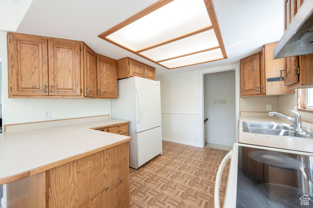 Kitchen featuring freestanding refrigerator, a sink, range, and light countertops