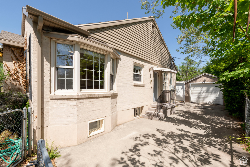 View of side of home featuring brick siding, an outdoor structure, and a detached garage