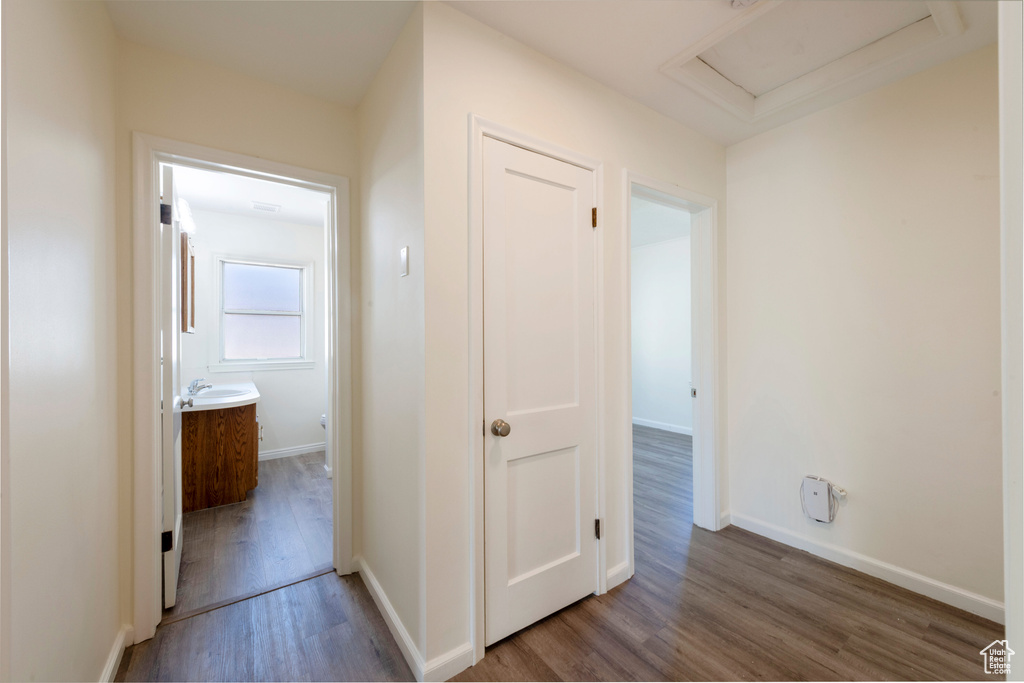 Corridor featuring wood finished floors, attic access, baseboards, and a sink