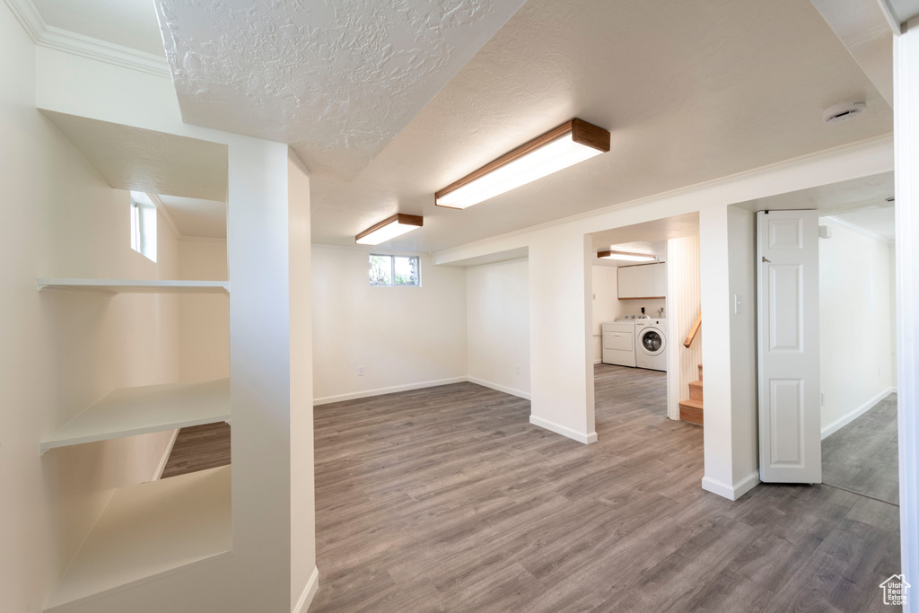 Below grade area with washer and clothes dryer, wood finished floors, baseboards, stairway, and ornamental molding