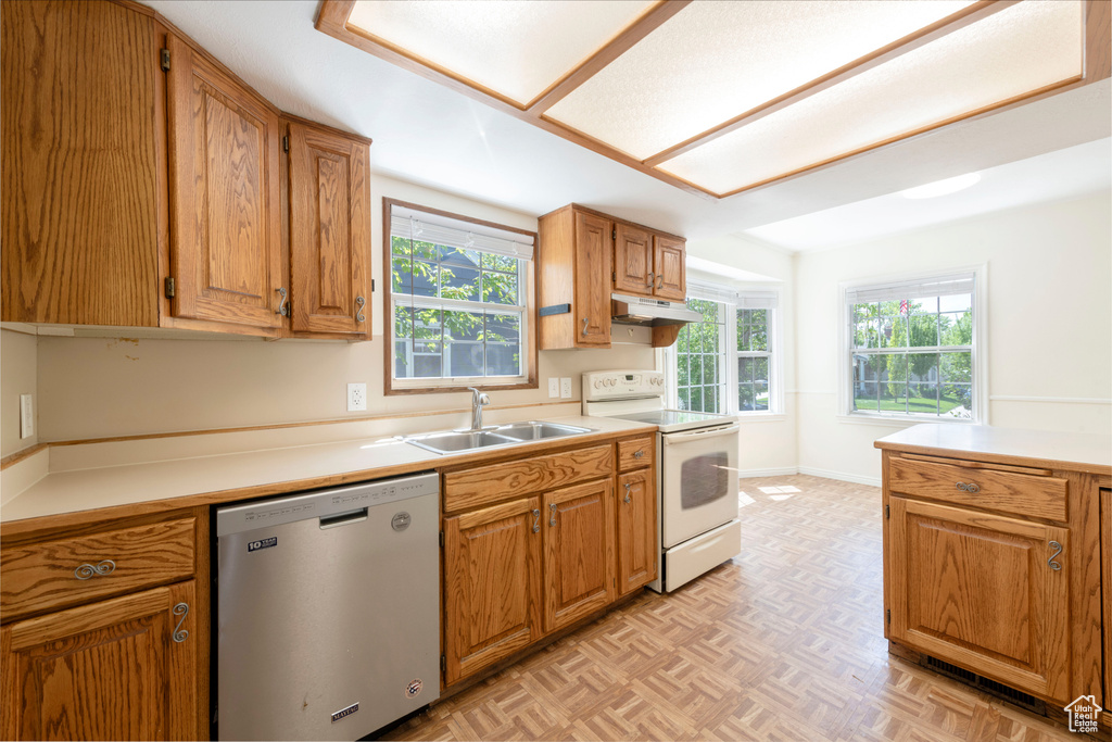 Kitchen with dishwasher, white range with electric stovetop, a sink, under cabinet range hood, and light countertops