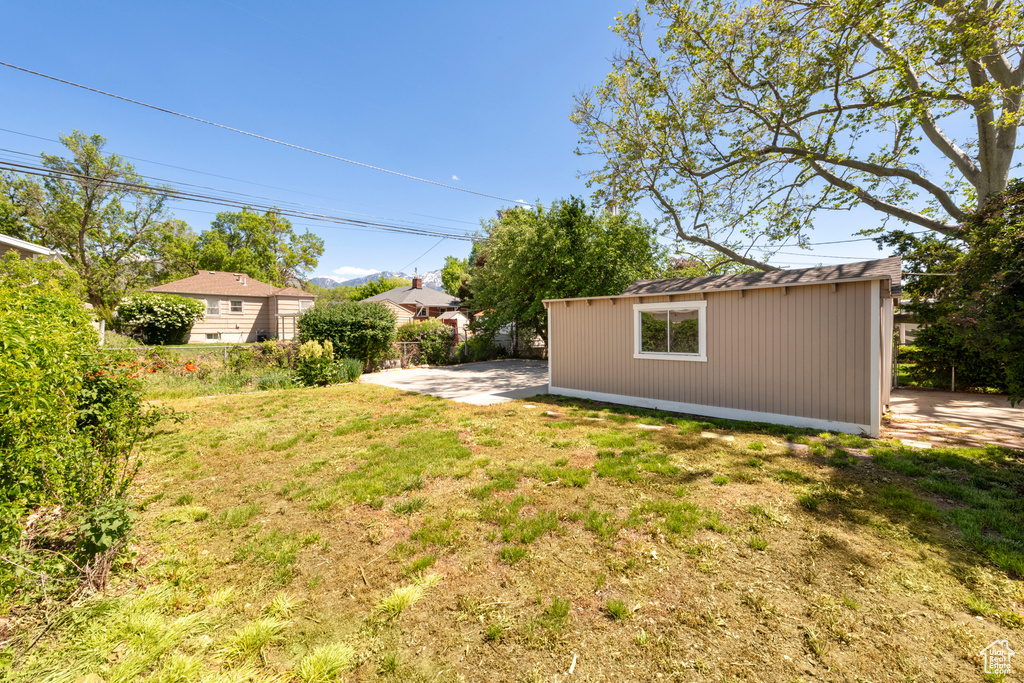 View of grassy yard featuring an outbuilding and a patio area