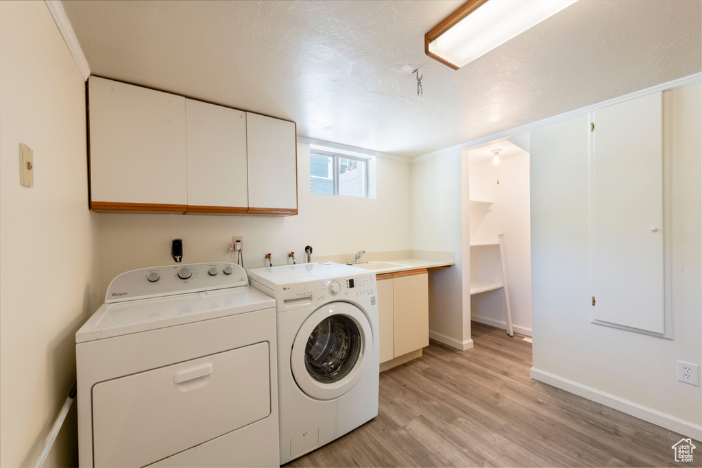 Laundry area featuring cabinet space, washer and dryer, light wood-style flooring, and baseboards