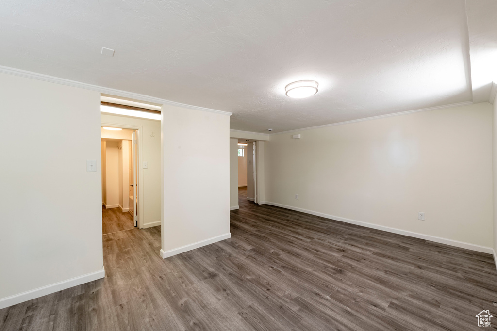 Unfurnished room featuring dark wood-style flooring, ornamental molding, and baseboards