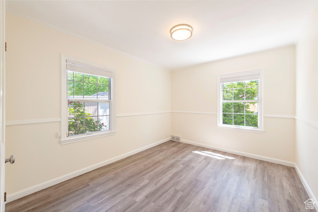 Empty room with plenty of natural light, wood finished floors, and baseboards