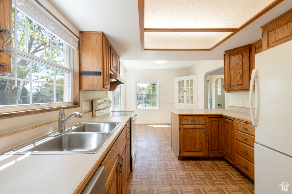 Kitchen featuring freestanding refrigerator, electric stove, a sink, and light countertops