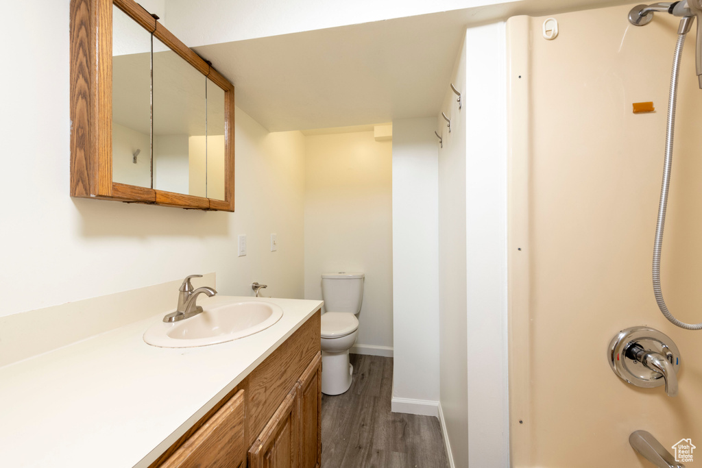 Full bath featuring wood finished floors, vanity, toilet, baseboards, and shower / bathtub combination