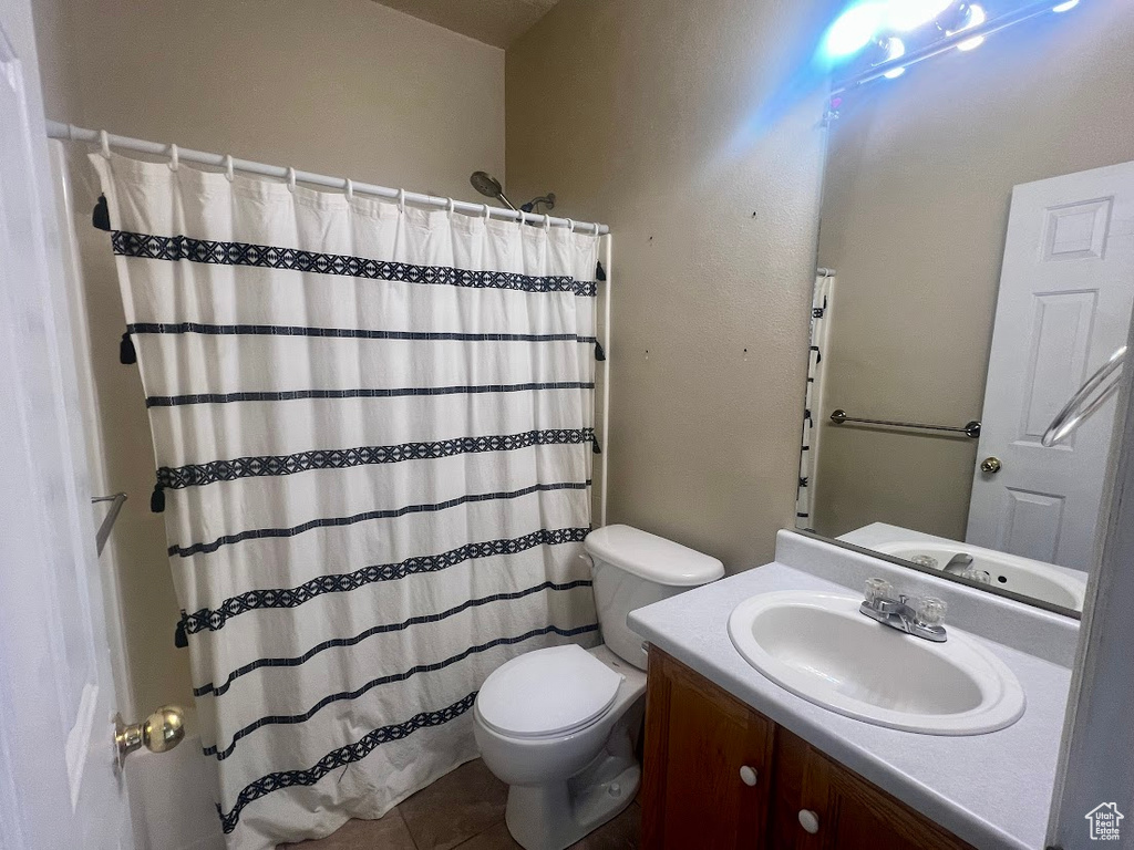 Bathroom with toilet, vanity, tile patterned flooring, and a shower with shower curtain