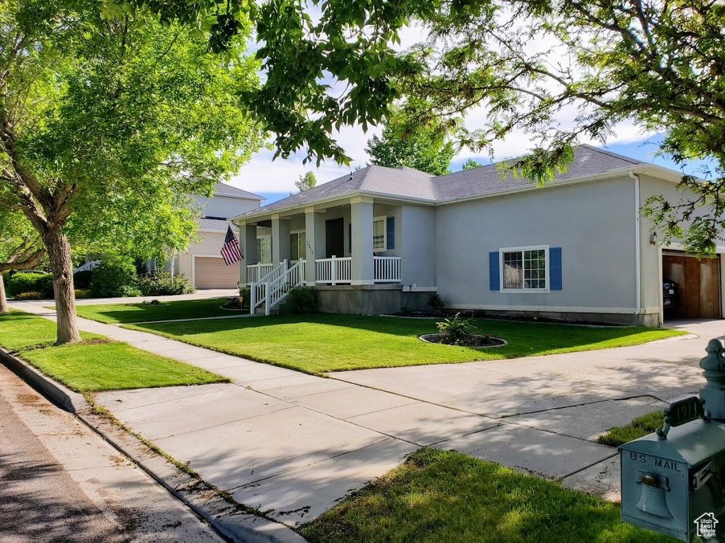 Single story home with a porch, stucco siding, a front yard, and concrete driveway